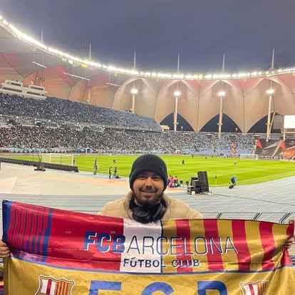 holding an fc barcelona flag at a stadium in riyadh